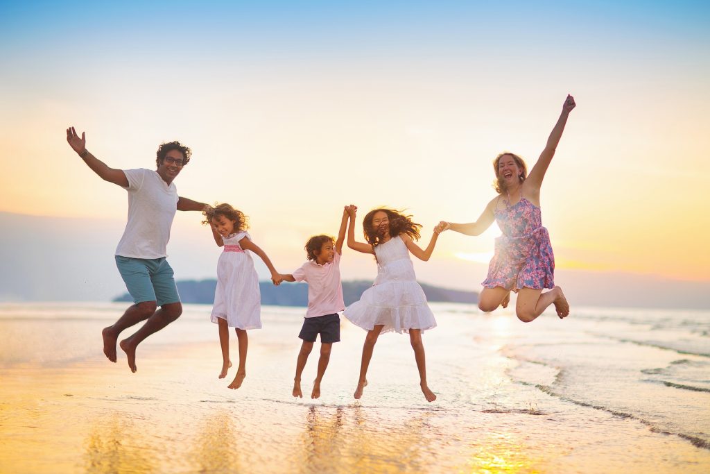 Family Walking On Tropical Beach At Sunset